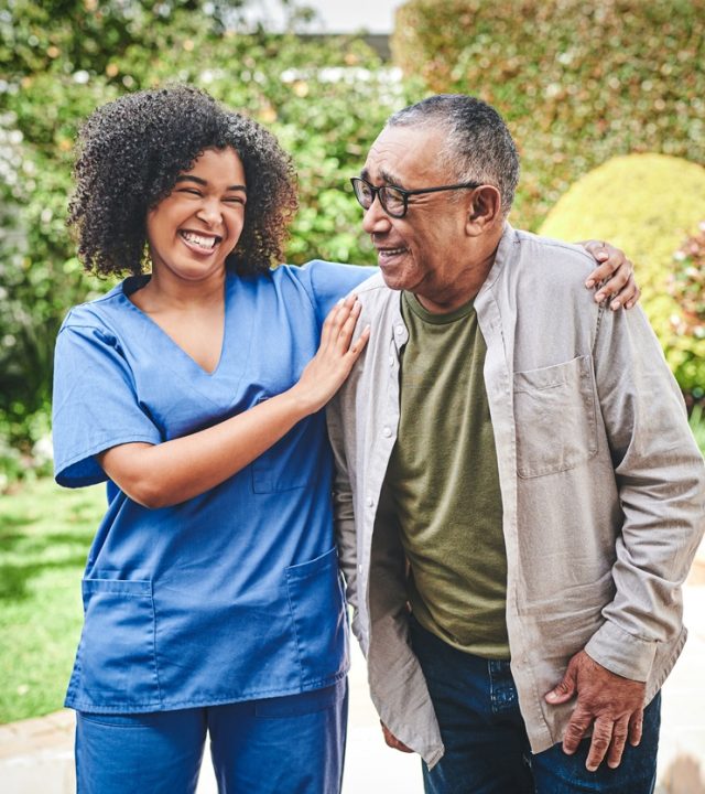 African American nurse smiling and hugging a patient who is an older man